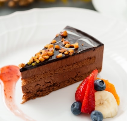チョコレートケーキにフルーツが添えられて白いお皿に乗っている画像